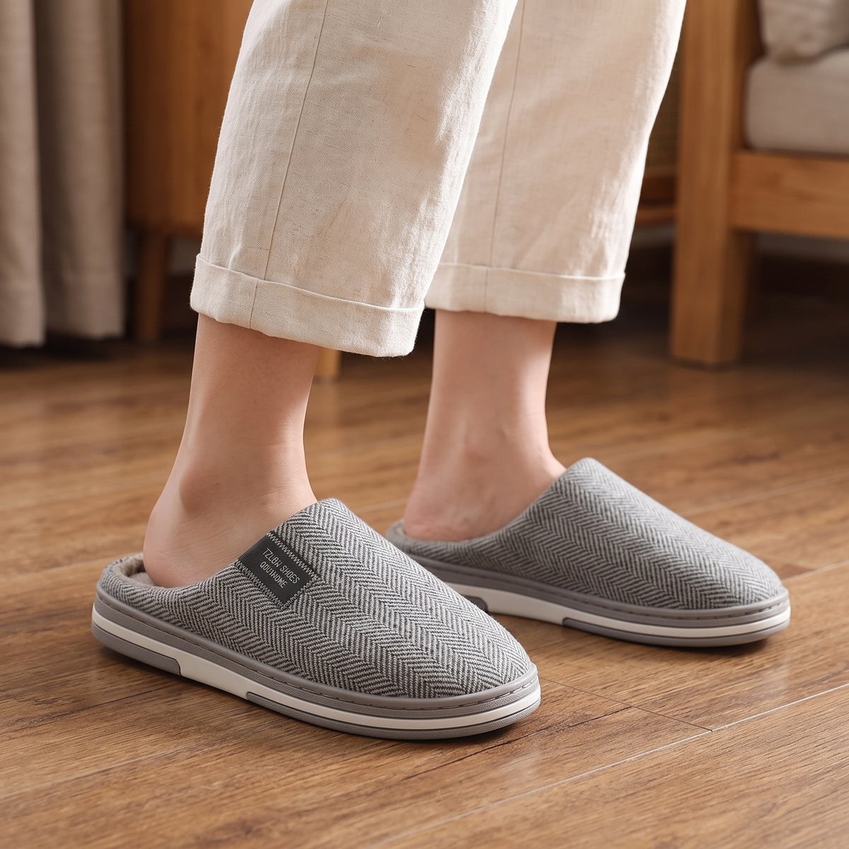 Chaussons femme Cosy gris clair à chevrons portés sur parquet